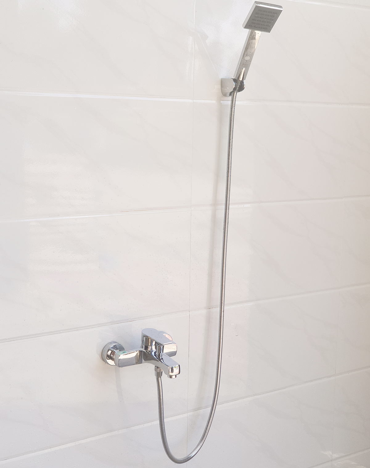 Hình ảnh củ sen nóng lạnh Eurolife EL-JAS 01 lắp đặt hoàn chỉnh cùng tay sen, dây sen 150cm và bát gác trên tường phòng tắm.
